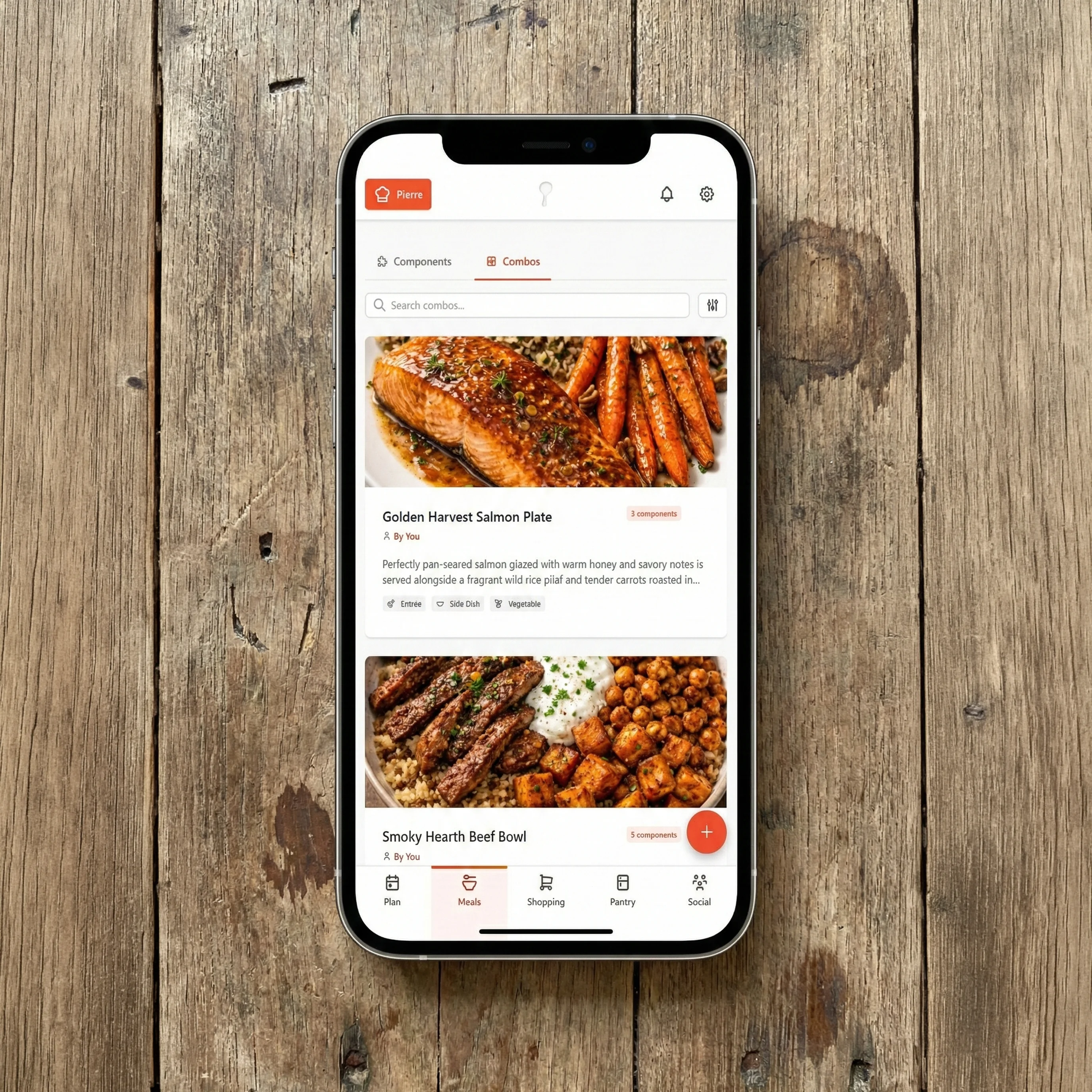 Smartphone displaying GoodSpoon meals page on wooden table, showing organized digital cookbook with recipe categories and favorites