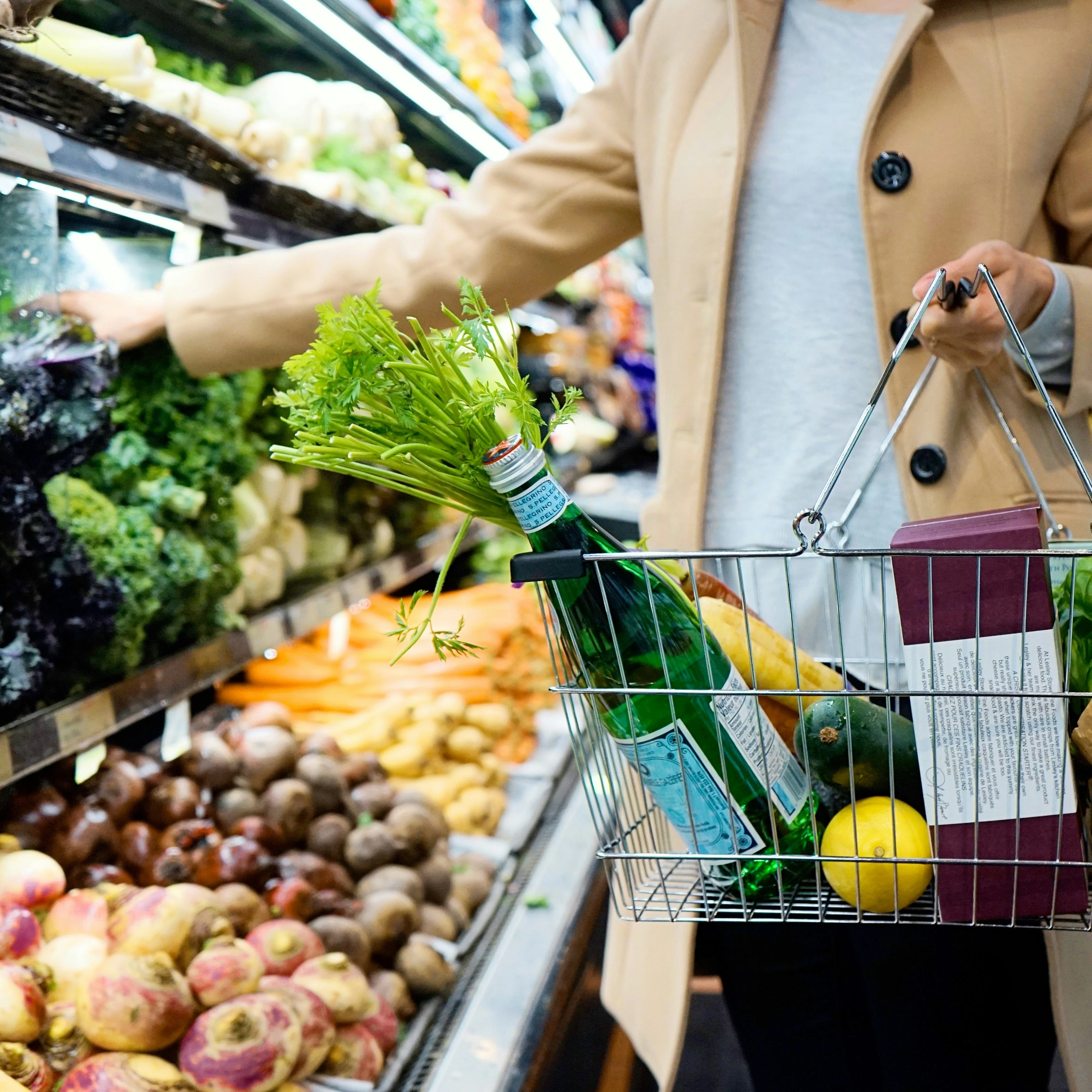 Person grocery shopping with cart, checking off items from their GoodSpoon shopping list